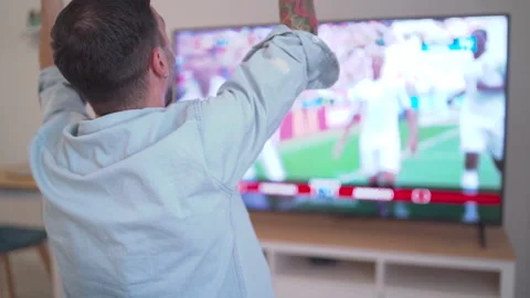 Slow motion cheering happy fan celebrating win watching blurry tv at home Stock Footage 204851265