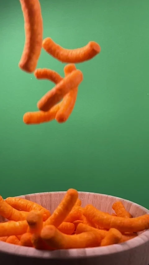 Slow motion of cheese puffs falling into a wooden bowl, vertical Stock Footage 345154577
