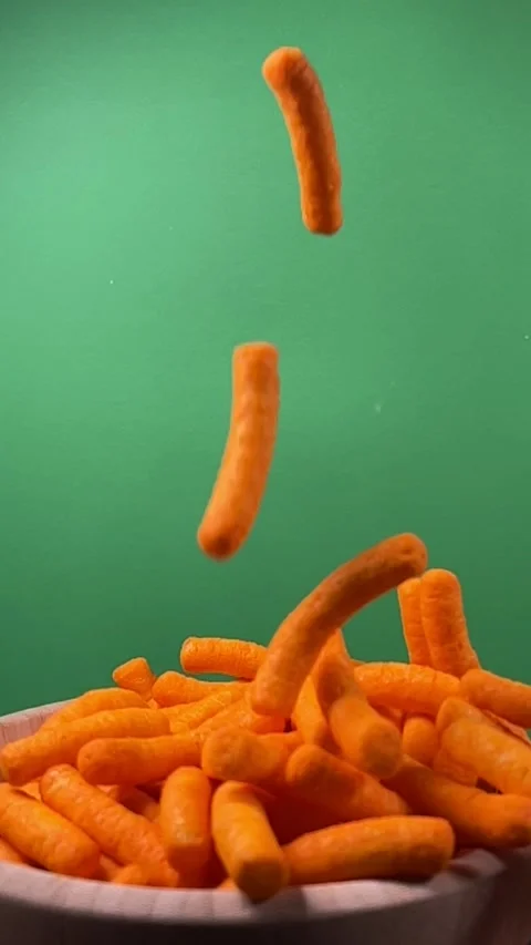 Slow motion of cheese puffs falling into a wooden bowl, vertical Stock Footage 345154578