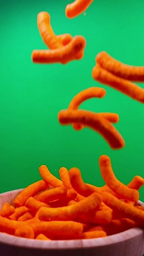 Slow motion of cheese puffs falling into a wooden bowl, vertical Stock Footage 345154587