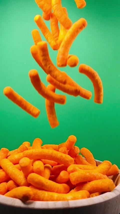 Slow motion of cheese puffs falling into a wooden bowl, vertical Stock Footage 345154698