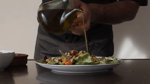 Slow motion of a Chef adding olive oil to a salad. Stock Footage 128288588