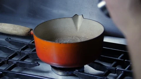 Slow motion Chef adding pepper to pan of boiling soup water in kitchen, steam Stock Footage 86536319