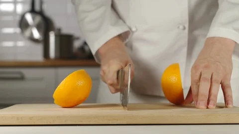 SLOW MOTION: Chef Chopping A Whole Fresh Orange On Wooden Board While Cooking Stock Footage 114797489