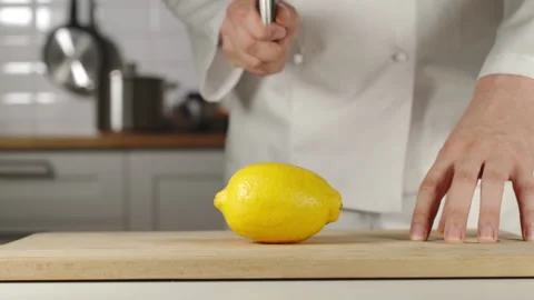 SLOW MOTION: Chef Chopping A Whole Fresh Lemon On Wooden Board While Cooking Видео 161687903