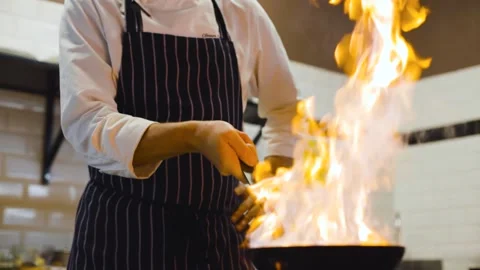 Slow motion of chef cooking with fire provokes flames in pan in a Stock Footage 165372008