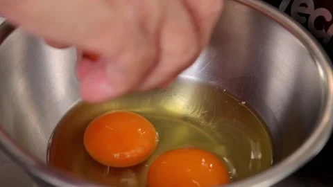 Slow motion of chef cracking egg into stainless bowl reveal egg yolk Video stock 159004276
