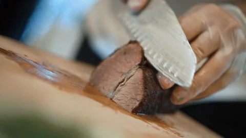 Slow motion a chef in gloves cuts with knife a steak on wood board Stockbeeldmateriaal 136441499