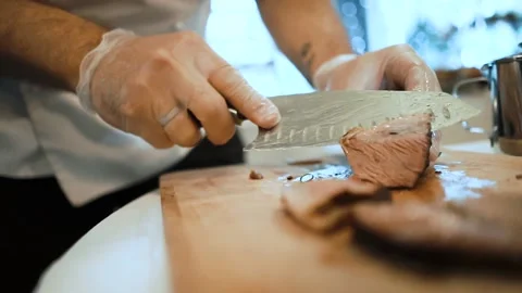 Slow motion a chef in gloves cuts juicy meat steak on a wooden board by a knife 스톡 동영상 136441528