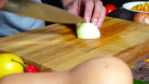 Slow motion of chef hands in home kitchen cutting an onion. Video stock 302300242
