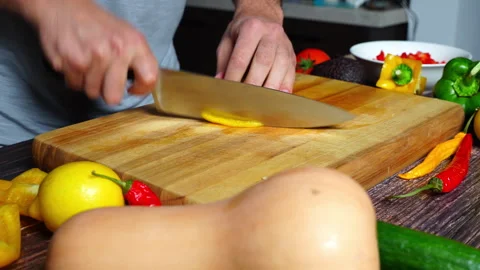 Slow motion of chef hands in home kitchen cutting an orange bell pepper on .. 库存影片 302303501
