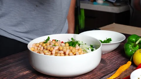 Slow motion of chef in home kitchen adding flat parsley to bean salad Video stock 302299723