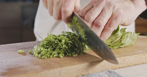 Slow motion of chef knife slicing celery leaves Stock Footage 125534340
