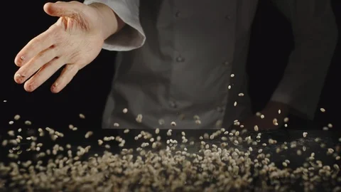 SLOW MOTION: Chef Pouring A Handful Of Raw Pearl Barley Over The Black Table Video stock 118788701