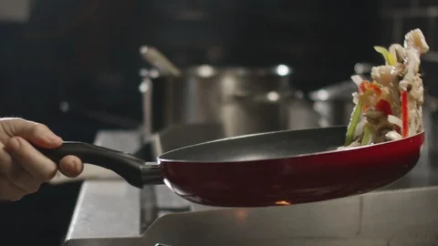 Slow motion chef tosses ingredients in frying pan Stock Footage 114416883