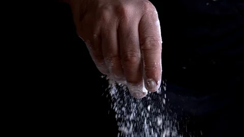 Slow motion of a Chef's hand spreading flour on a black background Stock Footage 128504542