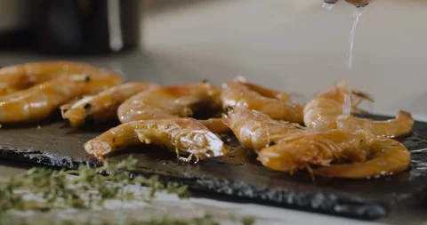 Slow motion chef's hand squeezes a half cut lemon over plate of gourmet shrimp. Stock Footage 124004725