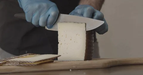 Slow motion of a chef's hands with protective gloves cutting cheese. Stock Footage 129671936
