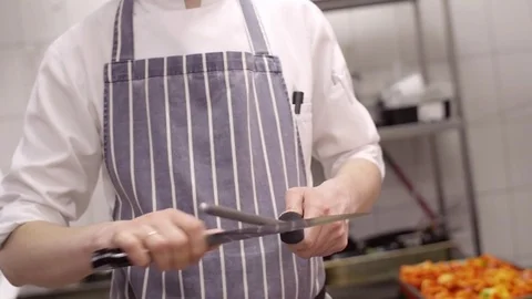 Slow motion chef's hands sharpens a professional steel knife close-up, standing Stock Footage 74531809