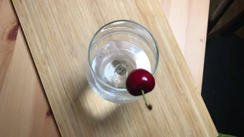 Slow motion cherry falling and hitting rim of wine glass Stock Footage 133134351