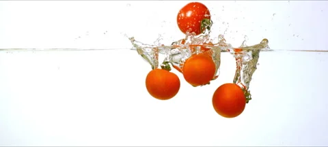 Slow-motion cherry tomatoes drop and splash into clear water. Commercial shot Stock Footage 323438807