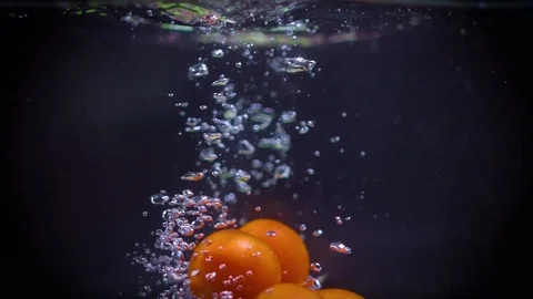 SLOW MOTION: Cherry tomatoes fall under water Video stock 122979653