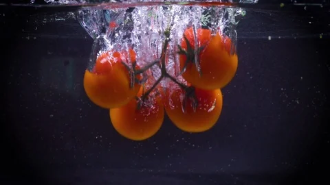 SLOW MOTION: Cherry tomatoes fall under water Stock Footage 122982153