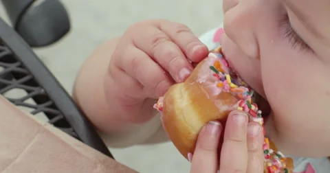 Slow Motion Child Bites the Top of a Sprinkled Donut Stock Footage 61468544