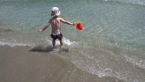 Slow motion child is drawing water in a toy bucket on the beach. Stock Footage 112367205