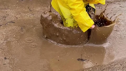 Slow motion a child jumping into a puddle Stock Footage 189988308