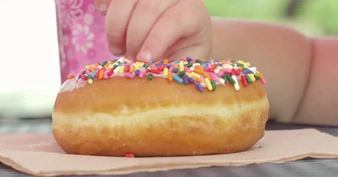 Slow Motion Child Picks Sprinkles Off of a Glazed Donut Stock Footage 61467837