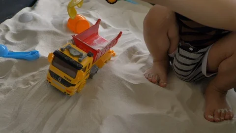 Slow motion, child playing dump toy in sand playground Stock Footage 94650425