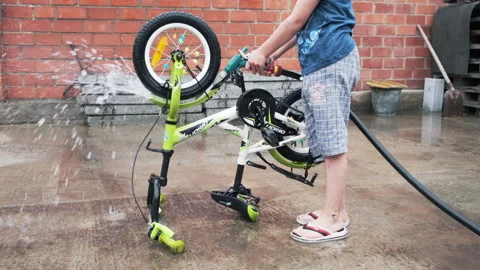 Slow motion. A child washes a children's bicycle Stock Footage 238913662