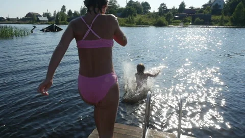 Slow motion children jumping off dock. Two girls, sisters jumping into the lake  Stock Footage 278867385