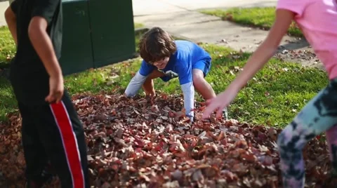 Slow motion of children playing with autumn leaves, throwing them in the air Stock Footage 63474380