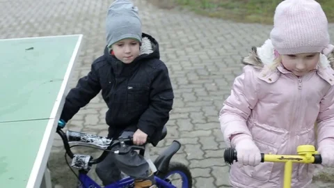 Slow motion. Children ride a mini scooter and bicycle. Stock Footage 71727710