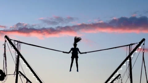 Slow motion: children silhouettes are jumping on bungee trampoline against sky Stock Footage 335048852