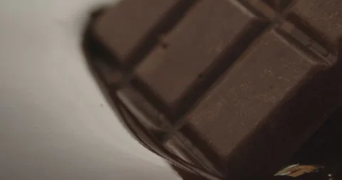 Slow Motion Chocolate Bar Falling into Liquid Chocolate - Rich Dessert Footage Stock Footage 276875319
