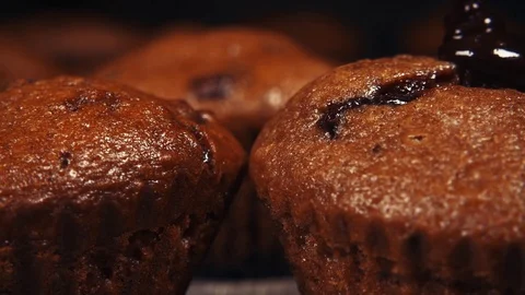 Slow motion chocolate icing pours two muffins close up Stock Footage 96171086