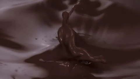 Slow motion: chocolate piece dropping into brown, chocolate liquid. UHD25p Stock Footage 249599989