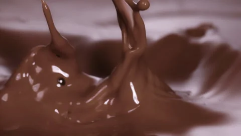 Slow motion: chocolate pieces dropping into brown, chocolate liquid. UHD25p Stock Footage 249599801