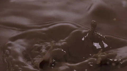 Slow motion: Chocolate pieces falling into chocolate milk. UHD25p Stock Footage 249595196