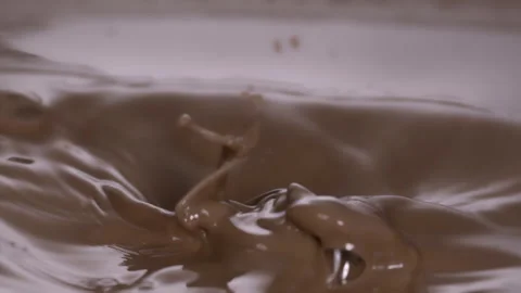 Slow motion: Chocolate pieces falling into chocolate liquid. UHD25p Stock Footage 249596866