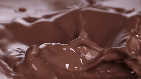 Slow motion: Chocolate pieces falling into chocolate liquid. UHD25p Stock Footage 249597519