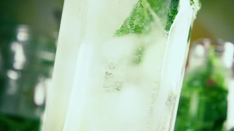 Slow motion citrus with ice and mint in a glass of water spinning Stock Footage 92320804
