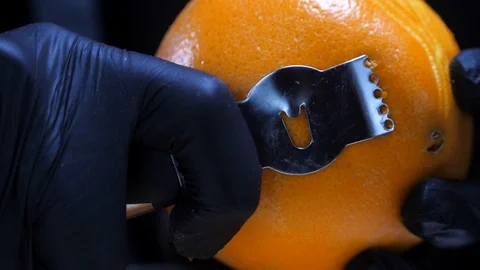 Slow motion of citrus zester grating peeling orange peel, oils spraying against Stock Footage 86564173
