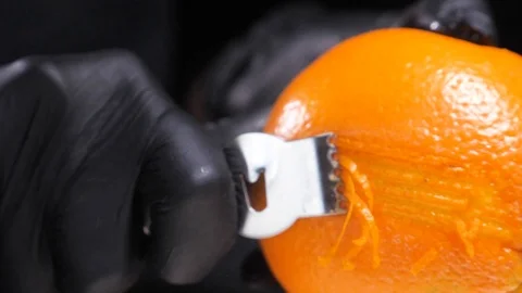 Slow motion of citrus zester grating peeling orange peel, oils spraying against Stock Footage 86564290