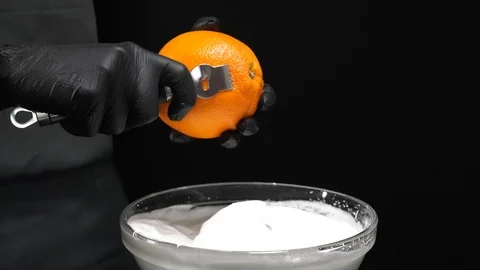 Slow motion of citrus zester grating peeling orange peel, oils spraying against Stock Footage 86564483
