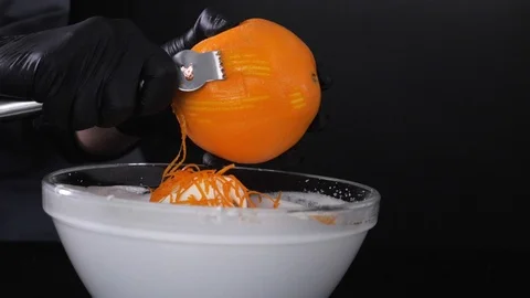 Slow motion of citrus zester grating peeling orange peel, oils spraying against Stock Footage 86564670