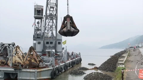 Slow motion. A clamshell crane on a floating platform works Video stock 114308600